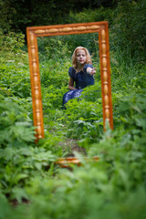 Obraz premium Portrait of beautiful little girl in the blue dress in nature with a mirror