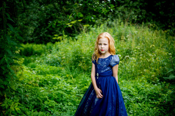 Portrait of beautiful little girl in the blue dress on the nature