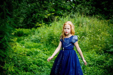 Obraz na płótnie Canvas Portrait of beautiful little girl in the blue dress on the nature