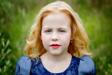 Fototapeta premium Portrait of beautiful little girl in the blue dress on the nature