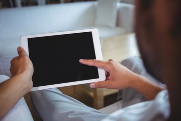 Mid section of man using digital tablet in living room
