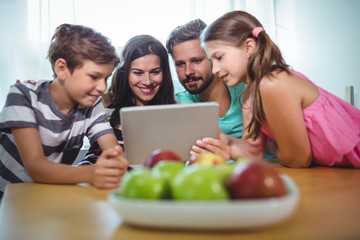 Family using digital tablet while sitting at table