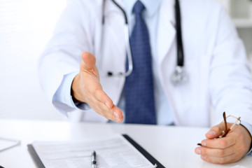 Fototapeta premium Male medicine doctor offering helping hand for handshake. Partnership and trust concept.
