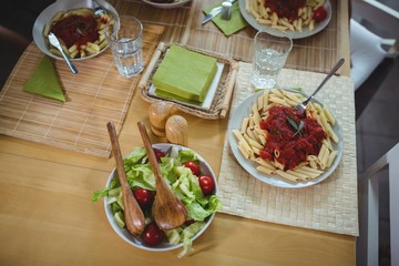 Plates of salad and pasta on dinning table