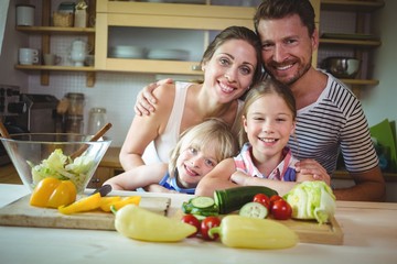 Portrait of happy family leaning on kitchen worktop