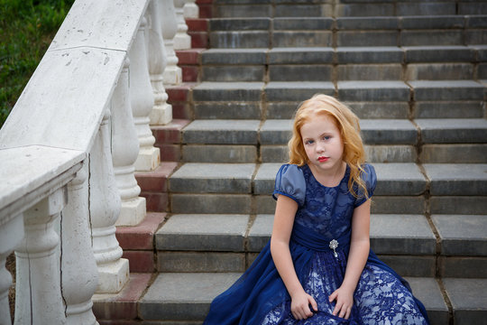 Portrait of beautiful little girl in the Park on the stairs