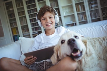 Boy sitting on sofa with dog listening to music
