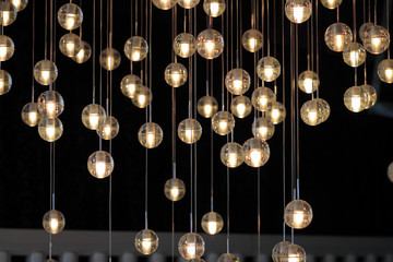  lighting balls on the chandelier in the lamplight,  light bulbs hanging from the ceiling, lamps on the dark background, selective focus, horizontal.