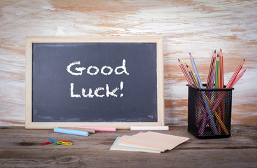 Good luck text on a blackboard. Old wooden table with texture