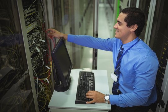 Technician working on personal computer while analyzing server
