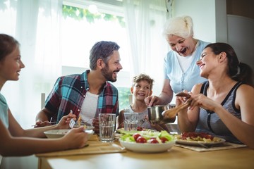 Elderly woman  serving meal to her family