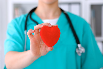 Female surgeon doctor with stethoscope holding heart.