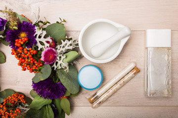 Seasonal skincare products with flowers on a wooden background