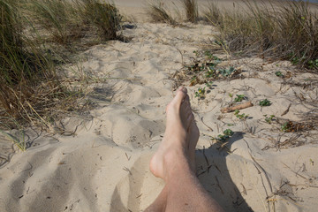 Man's feet relaxing on beach on sand