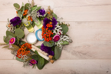Seasonal skincare products with flowers on a wooden background