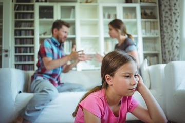 Sad girl listening to her parents arguing