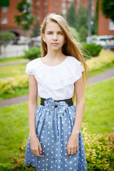 Fototapeta premium Portrait of a beautiful young girl in the Park skirt blouse nature fashion style