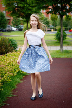 Portrait of a beautiful young girl in the Park skirt blouse nature fashion style