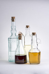 Transparent glass bottle with oil and vinegar on white background.