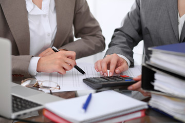 Two female accountants counting on calculator income for tax form completion hands closeup. Internal Revenue Service inspector checking financial document. Planning budget, audit  concept