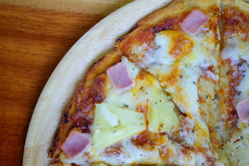 Hawaiian pizza in wooden plate place on wooden table.