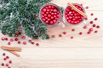 Tea with cranberries and cinnamon, artificial fir tree on the wooden background. Top view