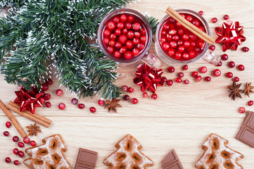Christmas background. Tea with cranberries and cinnamon, cookies, chocolate, spices and artificial fir tree on the wooden background. Top view