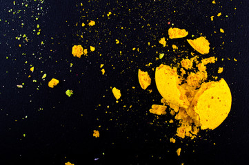 Crushed yellow macaroon. Tiny particles and black fone.Top view. Flat lay. Macro. Close up