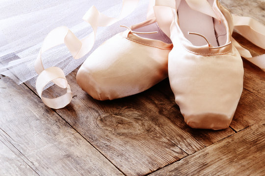 Image of silk pointe shoes and tutu on wooden floor