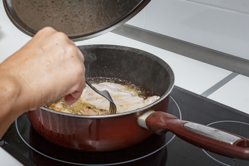 Mamá preparando en casa unas chuletas con salsa de cebolla caramelizada.