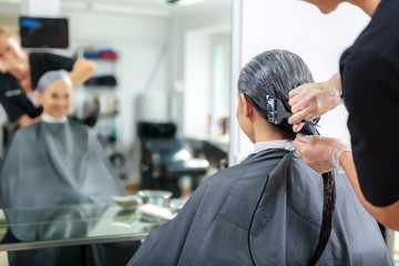 hands of hairstylist coloring client hair