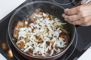 Mamá preparando en casa unas chuletas con salsa de cebolla caramelizada.