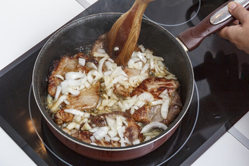 Mamá preparando en casa unas chuletas con salsa de cebolla caramelizada.