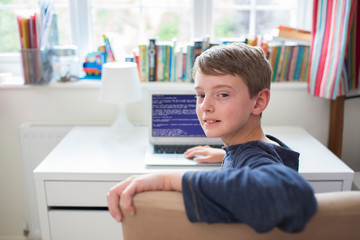 Teenage Boy In Bedroom Writing Computer Code