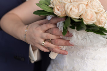 Obraz na płótnie Canvas A newly weding couple place their hands on a wedding bouquet sho