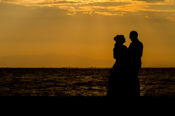 Silhouette of a young bride and groom on Sunset background