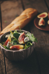 figs salad with blue cheese and ruccola on rustic wooden background. Homemade healthy food with seasonal fruits