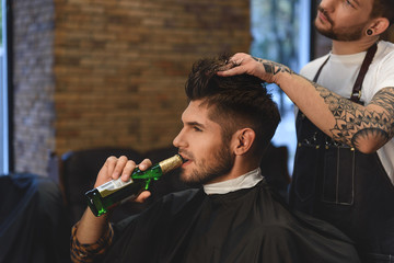 guy getting haircut while drinking