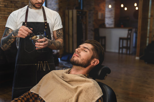 young man sitting at barbershop with closed eyes