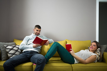 Happy young couple is relaxing at home and enjoying books.