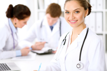 Fototapeta premium Happy doctor woman with medical staff at the hospital sitting at the table and discussing medical history