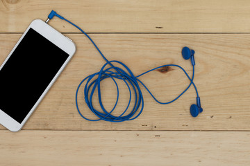 smartphone with headphones on the old wooden board