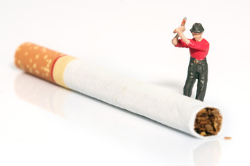Toy worker / View of miniature toy worker cutting cigarette.Focus on worker. Health concept.