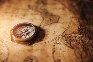 Close up of an old nautical compass on vintage map with sunshine