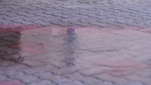 Spa&szlig; / Kind mit Gummistiefel springt in eine Pf&uuml;tze