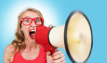 Naklejka premium Funny portrait of a girl shouting through the megaphone