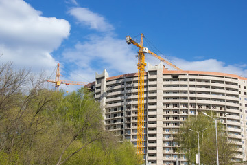 Unfinished concrete building and two building cranes near