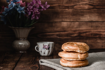 Eclairs stack on table with cup of coffee