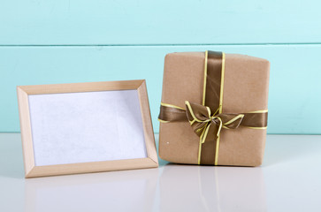 gift box in kraft paper and photo frame on wooden background.