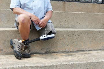 Amputee with legs crossed sitting on concrete bleachers